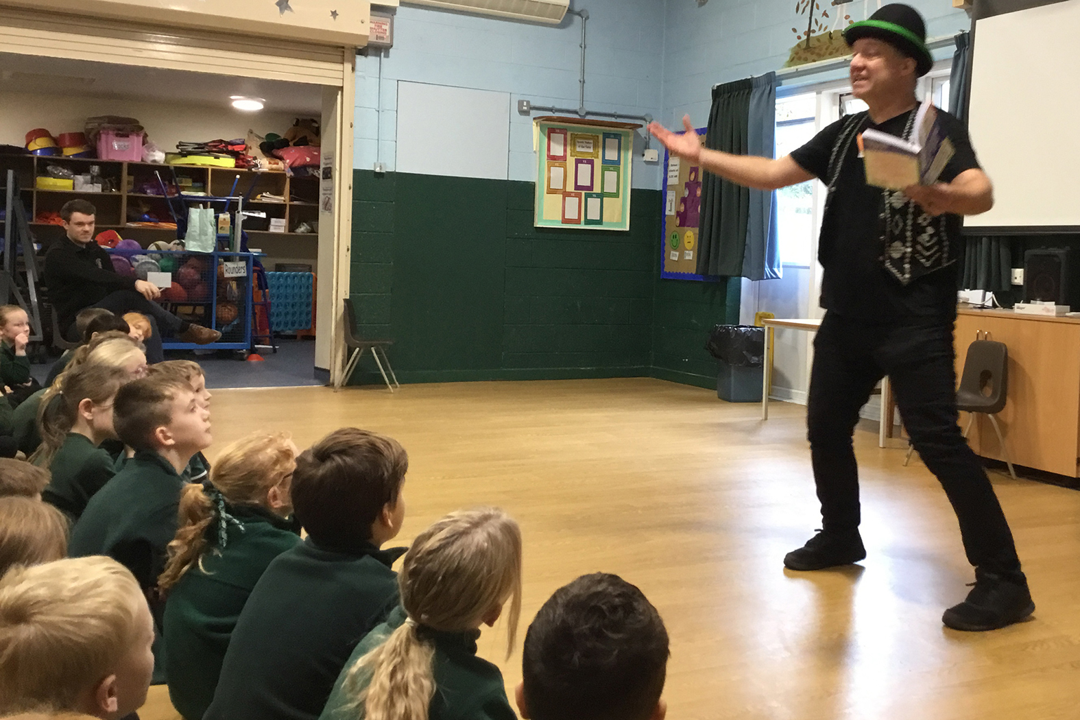 man performing tricks for schoold kids wearing a funny hat
